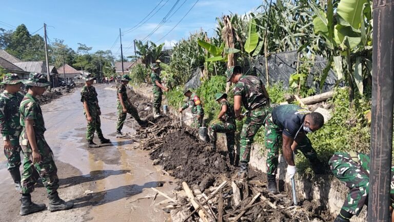 Personel Gabungan Kodim 0821 dan Yonif 527/BY Bersihkan Selokan di Jalur Vital Supiturang.